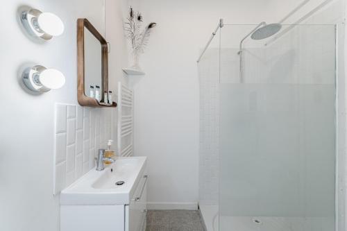 ein weißes Bad mit einem Waschbecken und einer Dusche in der Unterkunft Le Borély: Appartement climatisé avec 2 chambres, à 800m de la plage in Marseille