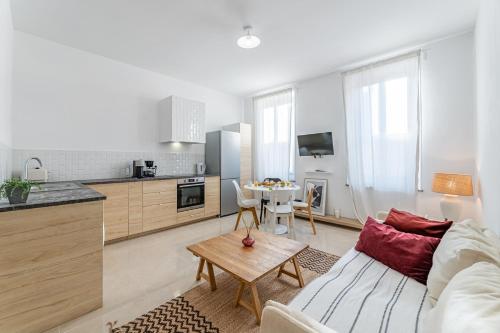 une cuisine et un salon avec un canapé et une table dans l'établissement Le Borély: Appartement climatisé avec 2 chambres, à 800m de la plage, à Marseille