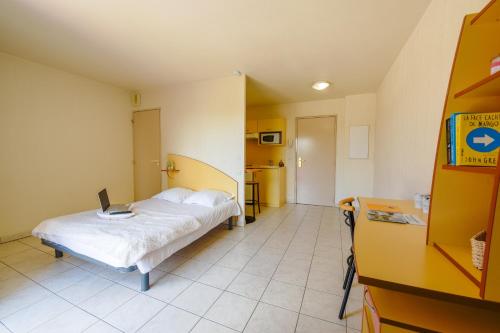 a bedroom with a bed with a laptop on it at Résidence Columba - Apparts meublés Agen Sud in Agen