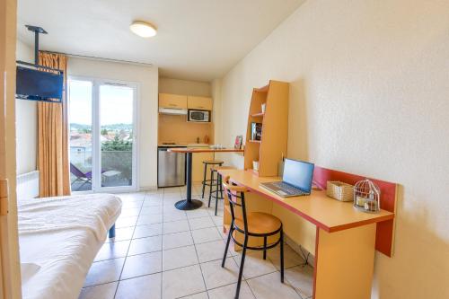 a room with a bed and a desk with a laptop at Résidence Columba - Apparts meublés Agen Sud in Agen