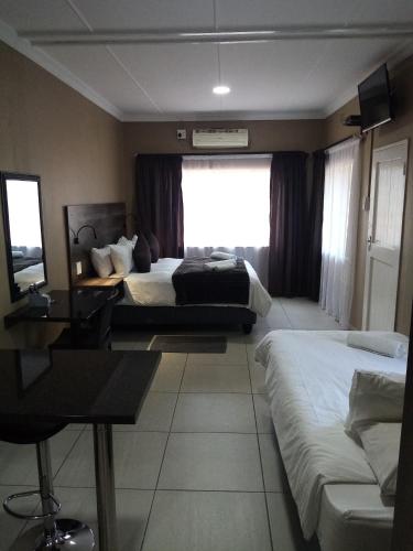 a hotel room with two beds and a window at Casa Leitao Lodge in Phalaborwa