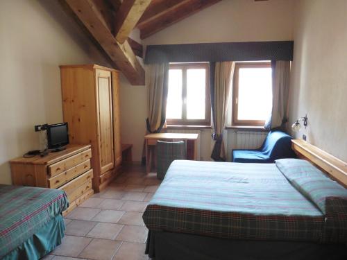 a bedroom with two beds and a tv and a chair at Hotel Mont Nery in Challand Saint Anselme
