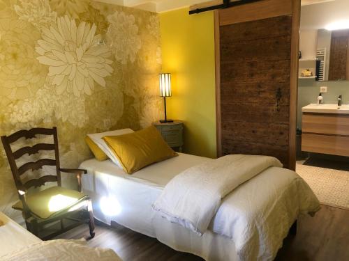 a bedroom with a bed and a chair and a sink at La Gatille in Villié-Morgon