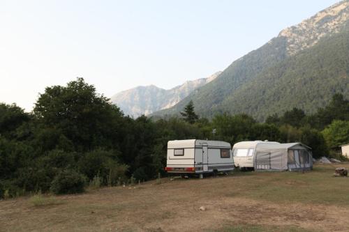 Hamiti Camping Center في Llogara: تم إيقاف سيارتين في حقل مع جبال في الخلف