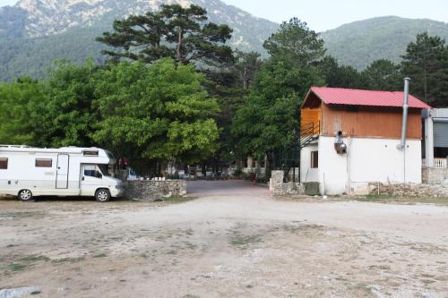 a rv parked next to a building and a house at Hamiti Camping Center in Llogara
