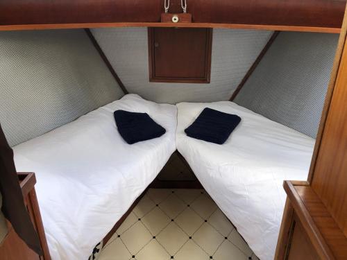 two beds in a small room with black pillows on them at La Vedette Hollandaise in Étaples