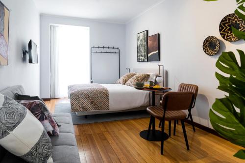 a bedroom with a bed and a table and a chair at Impar Studios Deluxe in Porto