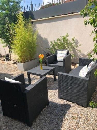 a patio with wicker furniture and a table with flowers at Studio Bijou Plage Antibes Juan-les-Pins in Antibes