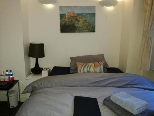 een slaapkamer met een bed en een schilderij aan de muur bij Lovet Homestay in Londen