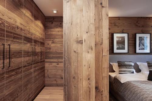 a bedroom with a wooden wall and a bed at HAHNENKAMM SUITE Ski-in Ski-out direkt an der Hahnenkammbahn in Kitzbühel