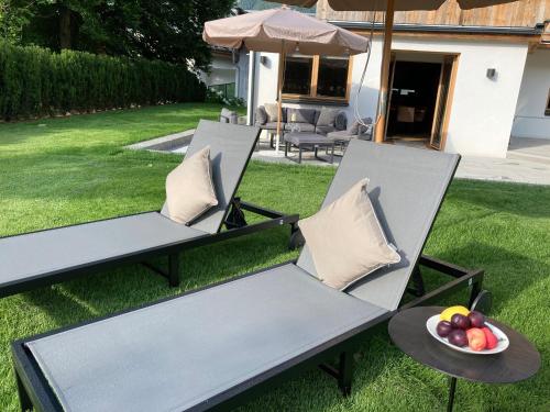two chairs and a bowl of fruit on the lawn at HAHNENKAMM SUITE Ski-in Ski-out direkt an der Hahnenkammbahn in Kitzbühel
