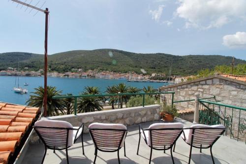 - un ensemble de chaises assises sur une terrasse près de l'eau dans l'établissement Apartment Karlo Vis, à Vis