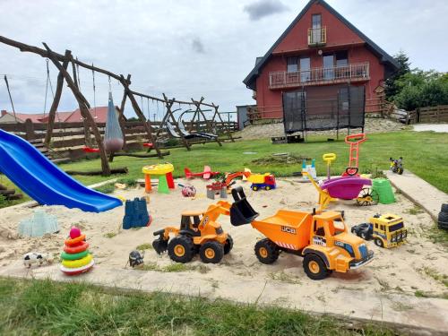 un parque infantil con juguetes en la arena frente a una casa en Noclegi u Banysia w sercu Gór Świętokrzyskich en Krajno Pierwsze