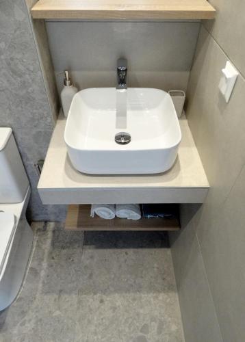 a white sink in a bathroom with a toilet at Sea-duction Studios in Nea Iraklia