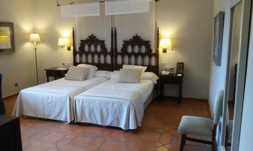 a bedroom with two beds and two tables and a chair at Parador de Cuenca in Cuenca