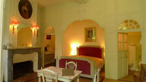 1 dormitorio con cama, mesa y chimenea en Château du Prada en Labastide-dʼArmagnac