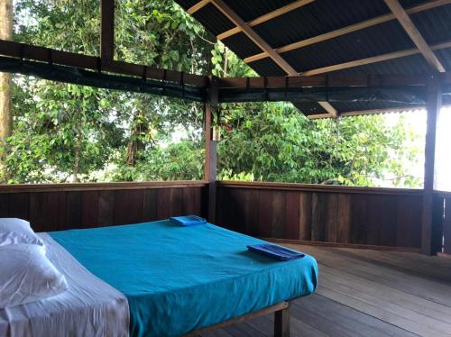 a bed on a wooden porch with trees at Punta Brava in Nuquí