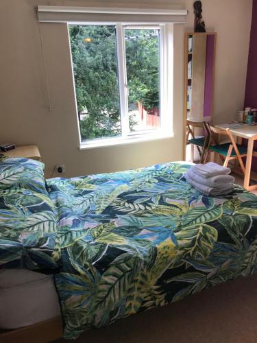 a bed with a colorful comforter in a bedroom with a window at Homestay Norwich in Norwich