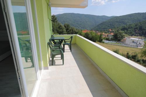 a balcony with a table and chairs and mountains at Bovan GREEN LAKE apartments in Soko Banja