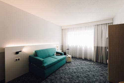 a living room with a green couch and a window at ibis Styles Nancy Laxou in Nancy