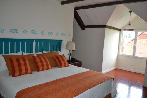 a bedroom with a large bed with orange pillows at Hotel Isla de Flores in Flores