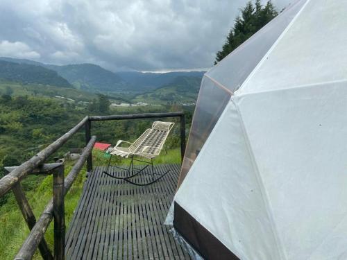 a tent and a chair on a balcony with a view at Alua Glamping in Pereira