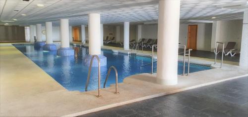 a swimming pool with columns and chairs in a building at La envia golf in Vícar