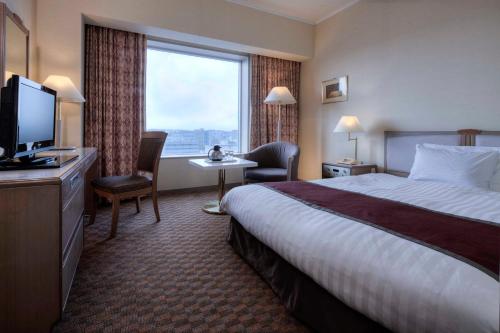 四日市市にある都ホテル 四日市のベッドと大きな窓が備わるホテルルームです。