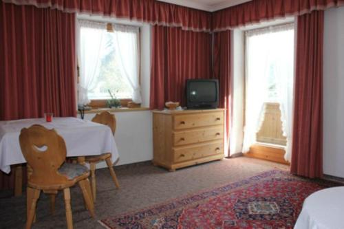 een slaapkamer met een tafel, een tv en ramen bij Waldvilla am See in Pertisau