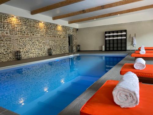 uma piscina com um banco vermelho e toalhas em Hôtel-Spa-Piscine Le Petit Castel Beuzeville-Honfleur em Beuzeville