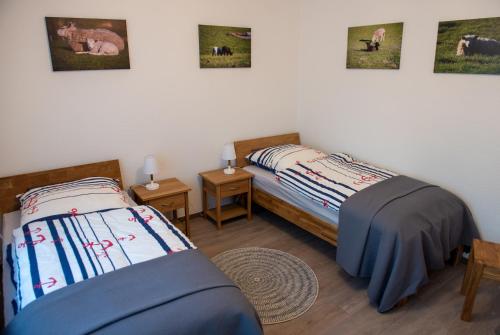 two beds in a room with pictures on the wall at Stüürhuus in Krummhörn