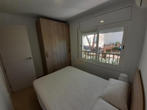 um pequeno quarto com uma cama e uma janela em Apartamentos Dins Mar Apto. 3 em Torredembarra