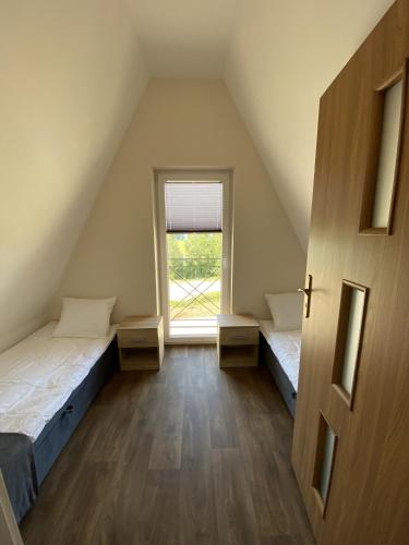 an attic room with two beds and a window at DOMKI NAD ŁOWISKIEM in Giżycko