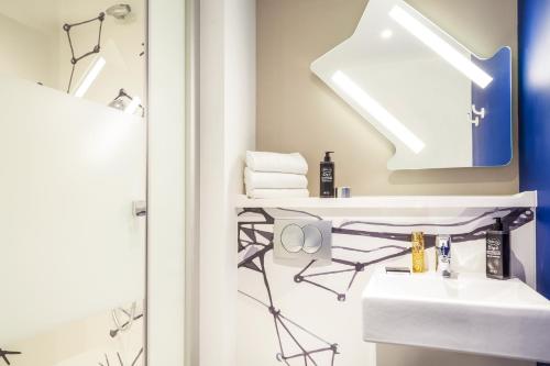 a bathroom with a sink and a mirror at Ibis Budget Montpellier Aéroport Parc Des Expos in Mauguio