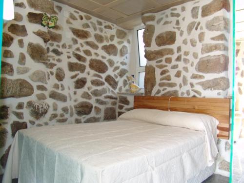 Bett in einem Zimmer mit einer Steinmauer in der Unterkunft Quinta de Santa Marinha in Arcos de Valdevez