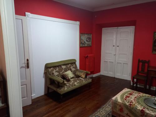 a living room with a chair and red walls at EL BORDON DE LA CASA BATALLON in Sarria