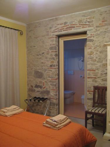 a bedroom with an orange bed and a stone wall at Corte Capitani in Capannori