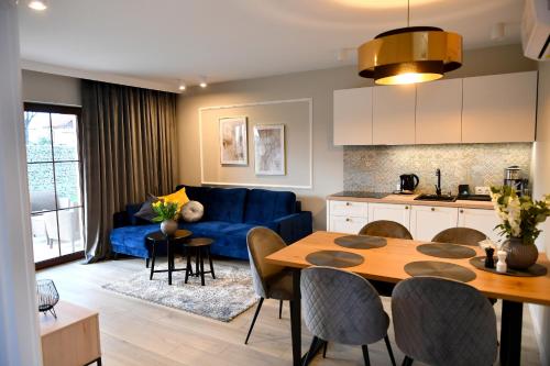 eine Küche und ein Wohnzimmer mit einem blauen Sofa und einem Tisch in der Unterkunft Apartamenty na Dworskiej in Spytkowice