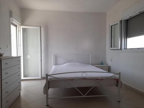 a white bedroom with a bed and a window at The veranda appartment with sea view in Agiokampos