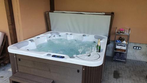 a bath tub filled with water with wine glasses in it at Lipno & Wellness Chata in Loučovice