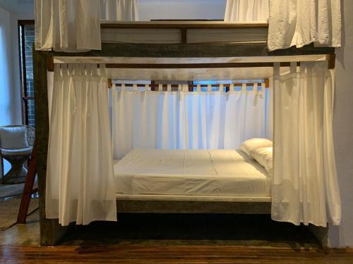 a canopy bed in a room with white curtains at Kaha Island Stay in Santa Monica