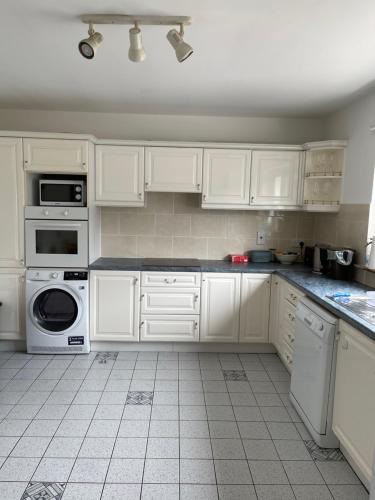 a white kitchen with white cabinets and appliances at Feather bed 3 bedroom house in Kinsale