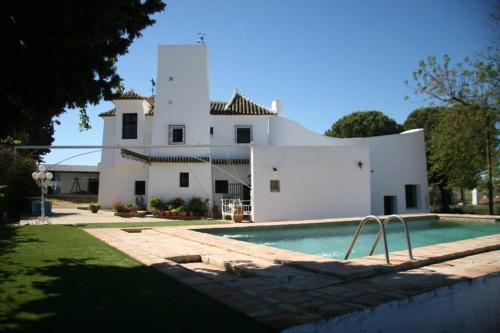 een wit huis met een zwembad ervoor bij Casa Rural Viña Meneses in Marchena