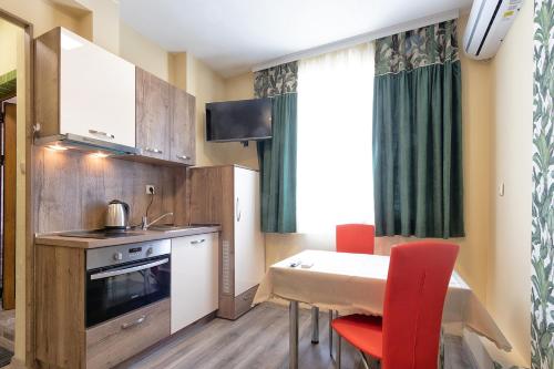 a small kitchen with a table and red chairs at BOLERO Suites in Varna City