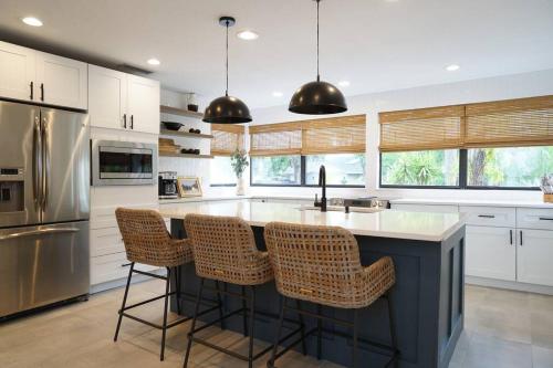 a kitchen with a large island with bar chairs at Remodeled 4BR Pool Home/IMG Golf View/Near Beaches in Bradenton