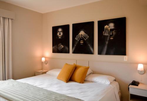 a bedroom with a bed with four pictures on the wall at Gandini Hotel in Itu