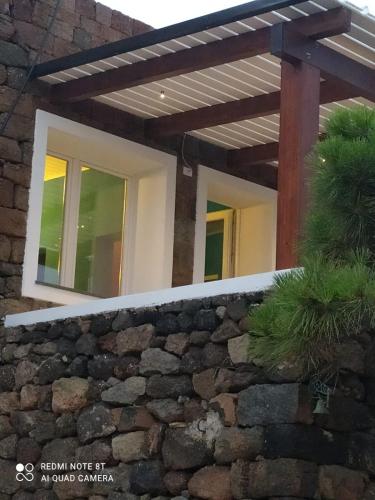 a house with a stone wall and a wooden pergola at TramontanaBeach in Tracino