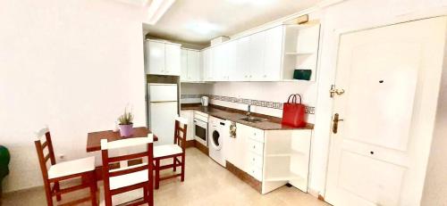 a kitchen with white cabinets and a table and chairs at 2 línea Cala del Palangre in Torrevieja