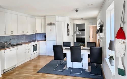 una cocina con armarios blancos y una mesa con sillas. en Björkö, lägenhet nära bad och Göteborg en Gotemburgo