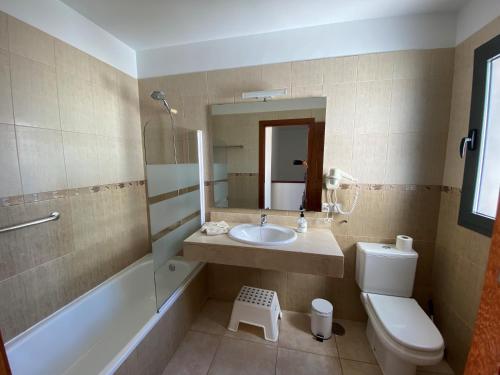 Un baño con lavabo, inodoro y espejo. en Varadero Nauplius, en Playa Blanca